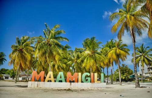 a large sign on a beach with palm trees at La Cabana, Maamigili in Maamigili