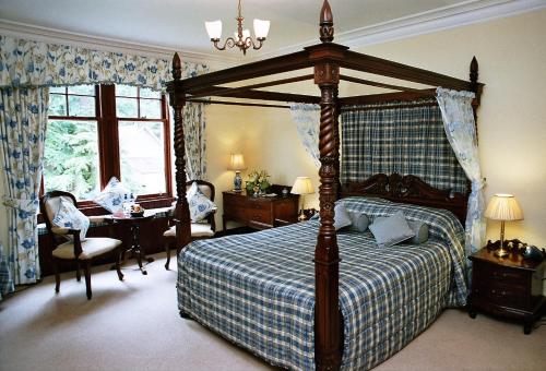 1 dormitorio con cama grande con dosel y escritorio en Tigh na Sgiath Country House Hotel, en Grantown-on-Spey