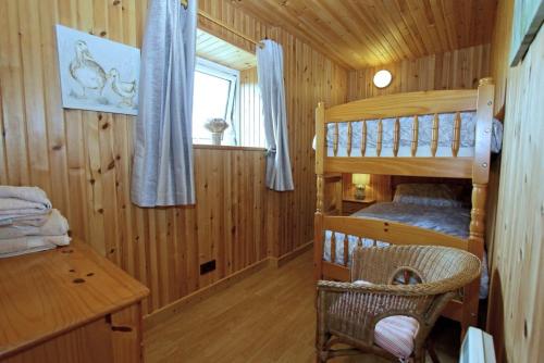 a bedroom with two bunk beds in a wooden cabin at Kelp Cottage in Pollachar