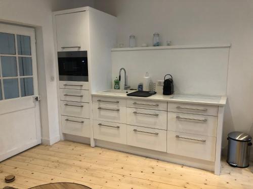 une cuisine avec des armoires blanches et un comptoir dans l'établissement Les Galets, à Saint-Valery-sur-Somme