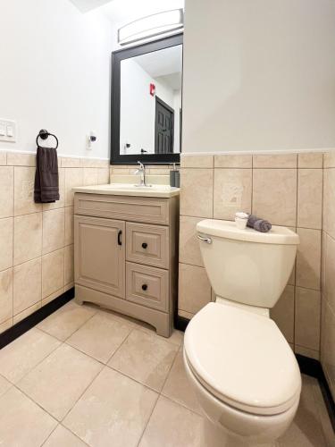 a bathroom with a toilet and a sink and a mirror at Boutique Studio Apartment on Grand Ave in Englewood