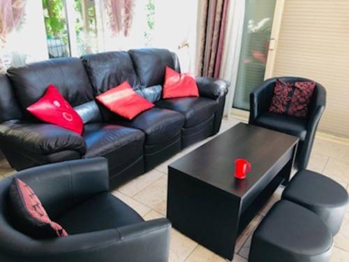 a living room with a black leather couch and a table at La petite maison de Paule in Amilly