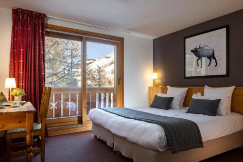 a bedroom with a bed and a window with a view at Hôtel Aalborg in Les Deux Alpes