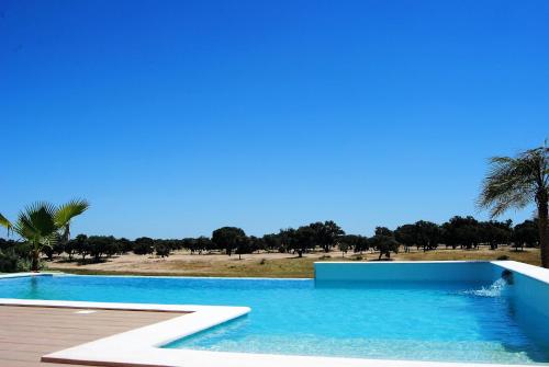 a blue swimming pool with a view of a field at Monte D'Vagar by Estilo Lusitano, com piscina privada in Grândola