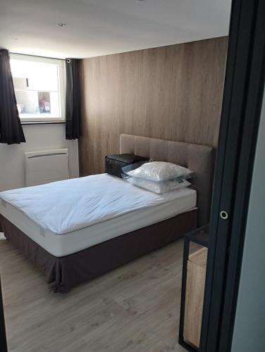 une chambre avec un lit avec des draps blancs et une fenêtre dans l'établissement Domaine de la Dune Gite entre Terre et Mer, à Saint-Martin-de-Varreville