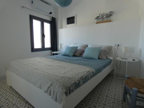 阿洛拉的住宿－Casa Alegría，白色卧室配有一张带蓝色枕头的大床