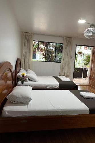 two beds in a bedroom with two windows at Hotel Principe I in Puerto Maldonado