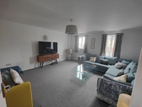 uma sala de estar com um sofá azul e uma televisão em Beach Break Aberavon Holiday Home by the Sea em Port Talbot