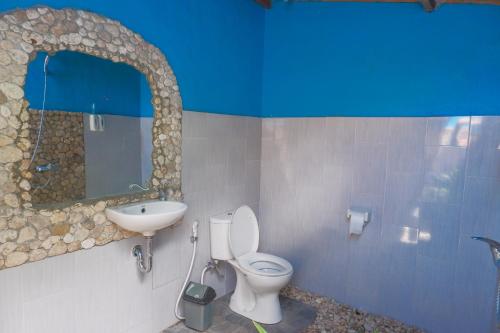 La salle de bains est pourvue de toilettes blanches et d'un lavabo. dans l'établissement The Tamban Jukung, à Nusa Penida