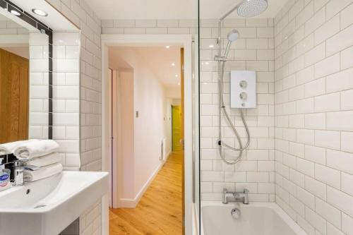 a bathroom with a shower and a sink and a tub at Central, Bright 2 Bed Flat - Pool & Sauna in Edinburgh