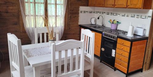 uma cozinha com um fogão e uma mesa e cadeiras brancas em ENTRE VIÑAS em Luján de Cuyo