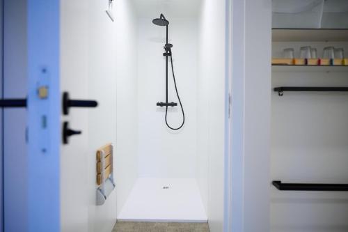 a shower in a bathroom with a white wall at La Compagnie des Moëres in Veurne