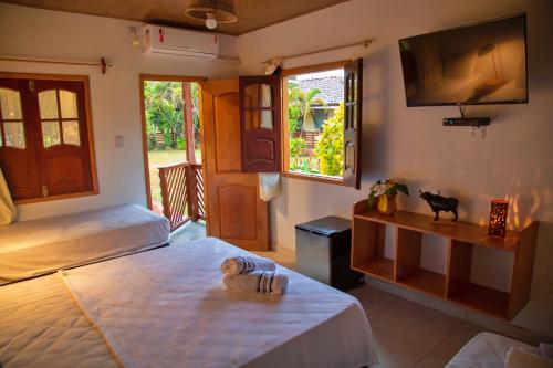 a bedroom with two beds and a flat screen tv at Pousada O Canto do Francês in Soure
