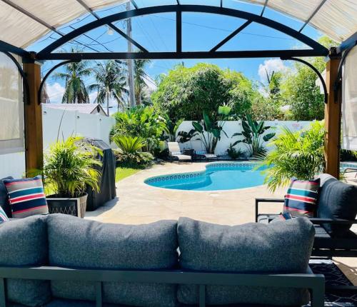 a patio with a couch and a swimming pool at Pompano home with private heated Pool 3D tour available in Pompano Beach