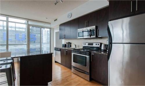 a kitchen with a stainless steel refrigerator and wooden cabinets at Toronto Downtown Core Two Bedroom Condo with CN Tower View, Free Parking in Toronto