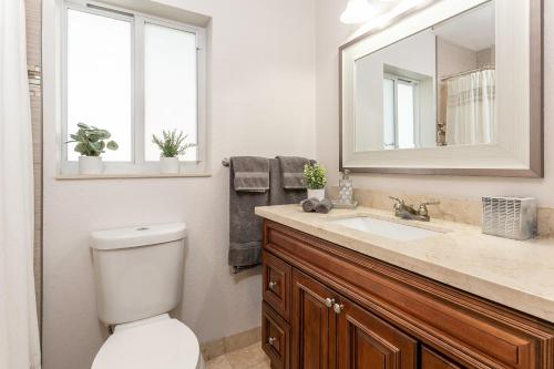 a bathroom with a toilet and a sink and a mirror at New! Tropical Escape in Pompano with private heated Pool, Spa, and Covered Pergola in Pompano Beach