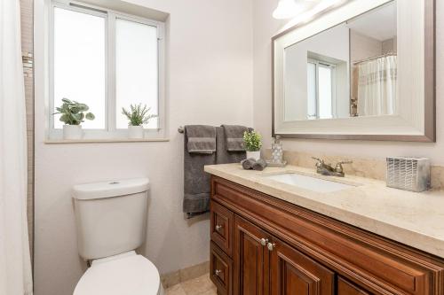 a bathroom with a toilet and a sink and a mirror at Pompano home with private heated Pool 3D tour available in Pompano Beach