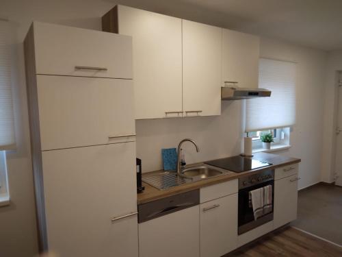 una cocina con armarios blancos y fregadero en Appartement Fam.Kremser, en Leutschach