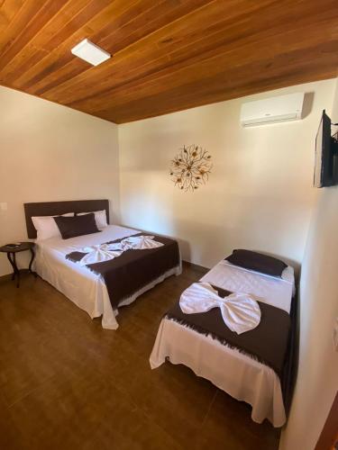 a bedroom with two beds and a clock on the wall at Pousada Cipó Cana in Santana do Riacho