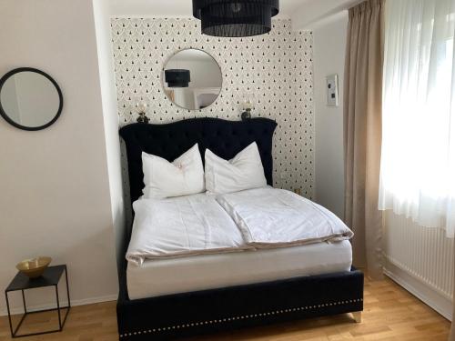 a bedroom with a bed with a black headboard and a mirror at SternenHimmel Gamlitz in Gamlitz