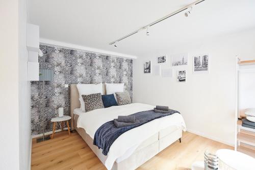 - une chambre blanche avec un lit et un mur recouvert de papier peint dans l'établissement Wohnträumerei Petit - Stilvoll eingerichtetes und ruhiges Design Apartment, à Göttingen