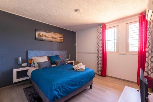 a bedroom with a blue bed and red curtains at Villa Comfort-Soleil in Kourou