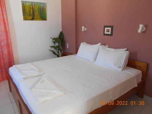 1 cama con sábanas blancas y almohadas en una habitación en Garifalia Studios, en Kalamaki