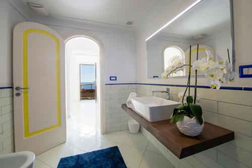 a white bathroom with a sink and a mirror at Aria di Mare, garden and Sea View in Positano in Positano