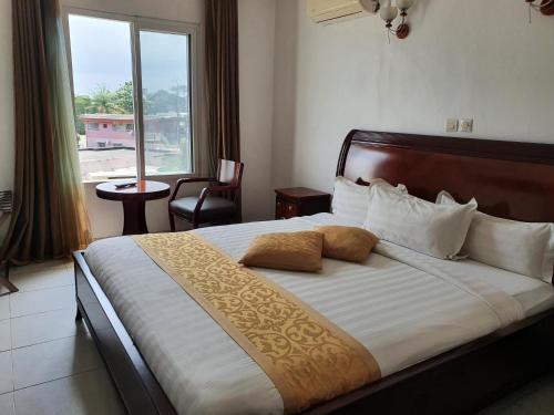 a bedroom with a large bed with a large window at Hotel Impérial in Libreville