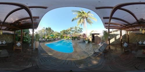 a pool at a resort with a palm tree in the background at Quari Quara BY MN Hotéis in Rio das Ostras