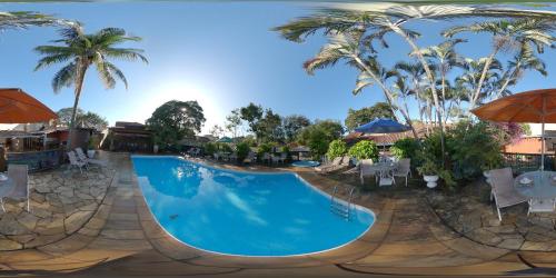 a pool at a resort with palm trees and umbrellas at Quari Quara BY MN Hotéis in Rio das Ostras