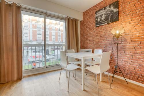 a white table and chairs in a room with a brick wall at Loft proche PARIS SAINT-LAZARE in Courbevoie