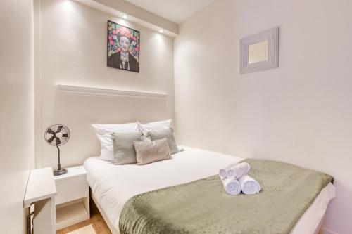 a small white bedroom with a bed and a desk at Loft proche PARIS SAINT-LAZARE in Courbevoie