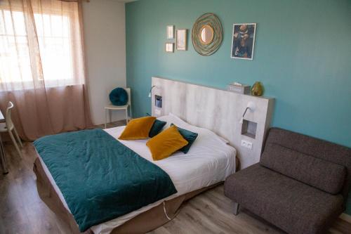 a bedroom with a bed and a chair at LOGIS - Hôtel Restaurant Du Canard in Hangest-sur-Somme