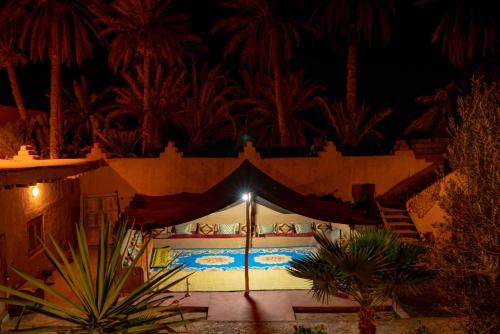 Aït BoukhaMaison etoile du desert的夜间在建筑物中间的帐篷
