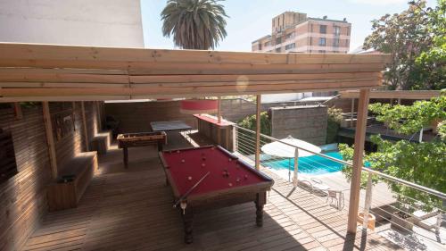 a pool table on a deck next to a swimming pool at Happy House Hostel in Santiago