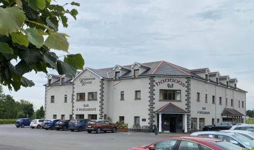 ein großes weißes Gebäude mit Autos auf einem Parkplatz in der Unterkunft Hannon's Hotel in Roscommon