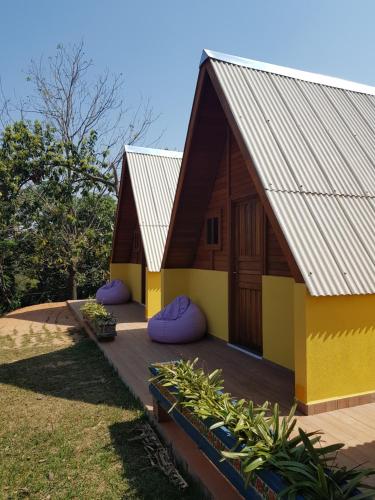 una casa con tetto spiovente e cuscini viola su una terrazza di Chalés Magia das Águas ad Águas de Lindóia