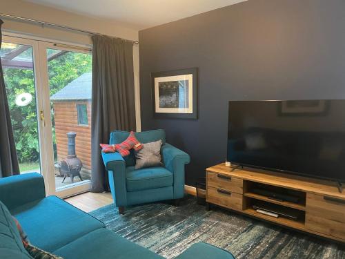 a living room with a blue couch and a flat screen tv at Linmore in Aviemore