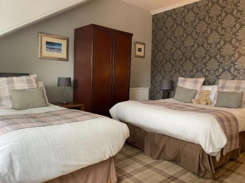 a bedroom with two beds with a teddy bear sitting on top at Gowanlea Guest House in Balloch