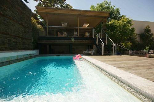 a swimming pool with a deck and a house at Happy House Hostel in Santiago