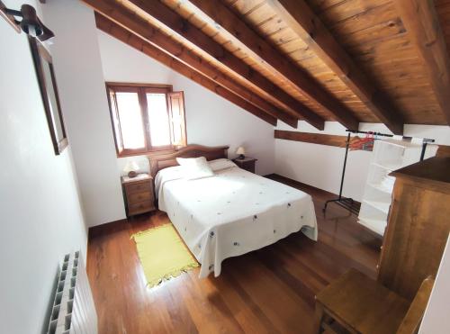 a bedroom with a white bed and a wooden ceiling at La Huertona in Pesaguero-La Parte
