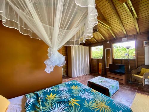 a bedroom with a bed and a tv in a room at Bungalow Kataliya in Petit-Bourg