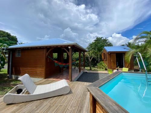 a deck with a chair next to a swimming pool at Bungalow Kataliya in Petit-Bourg