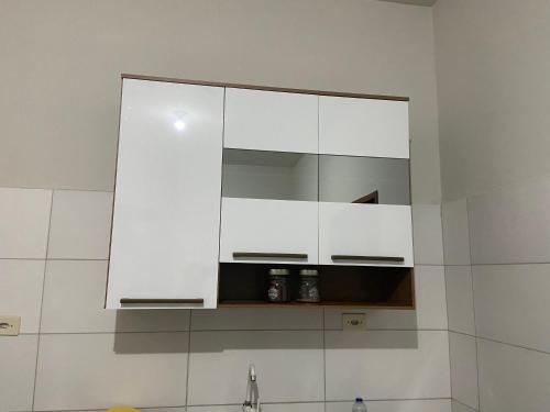 eine Küche mit weißen Schränken und einem Spiegel über einem Waschbecken in der Unterkunft Casa agradável no centro in Bananeiras