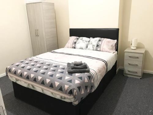 Schlafzimmer mit einem Bett mit einer schwarzen und weißen Bettdecke in der Unterkunft Air Host in Walsall