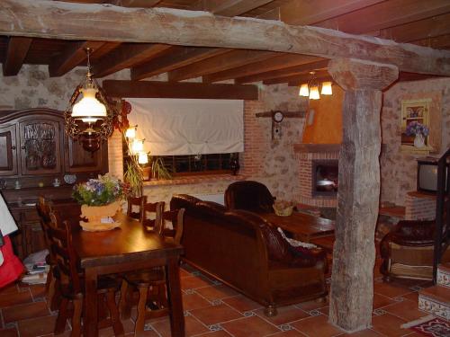sala de estar con mesa, sofá y chimenea en Casa Rural Pincherres, en Mata de Quintanar
