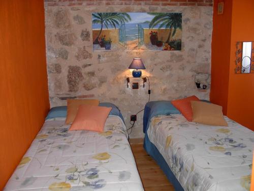 Duas camas num quarto com paredes cor de laranja em Casa Rural Pincherres em Mata de Quintanar