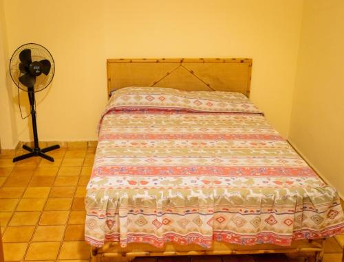 uma cama num quarto com uma ventoinha em 16SOLDAPRAIA Apartamento aconchegante próximo a praia na Praia Grande