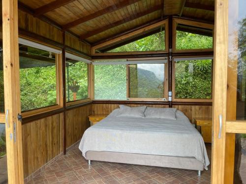 a bedroom with a bed in a room with windows at cabaña ecologica in Sasaima
